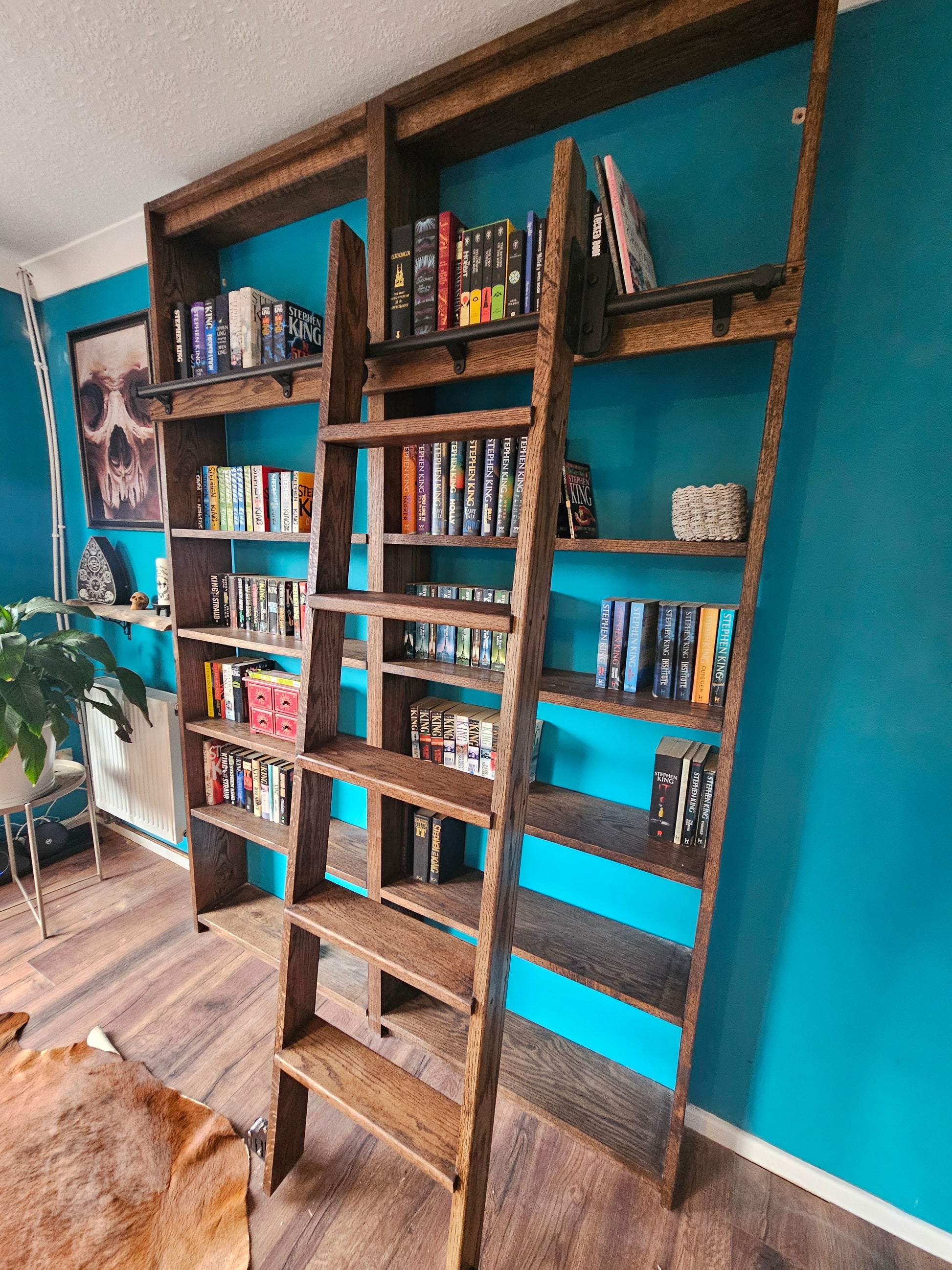 Wooden bookshelf against a blue wall with books and decorative items. Bookcase as a sliding ladder